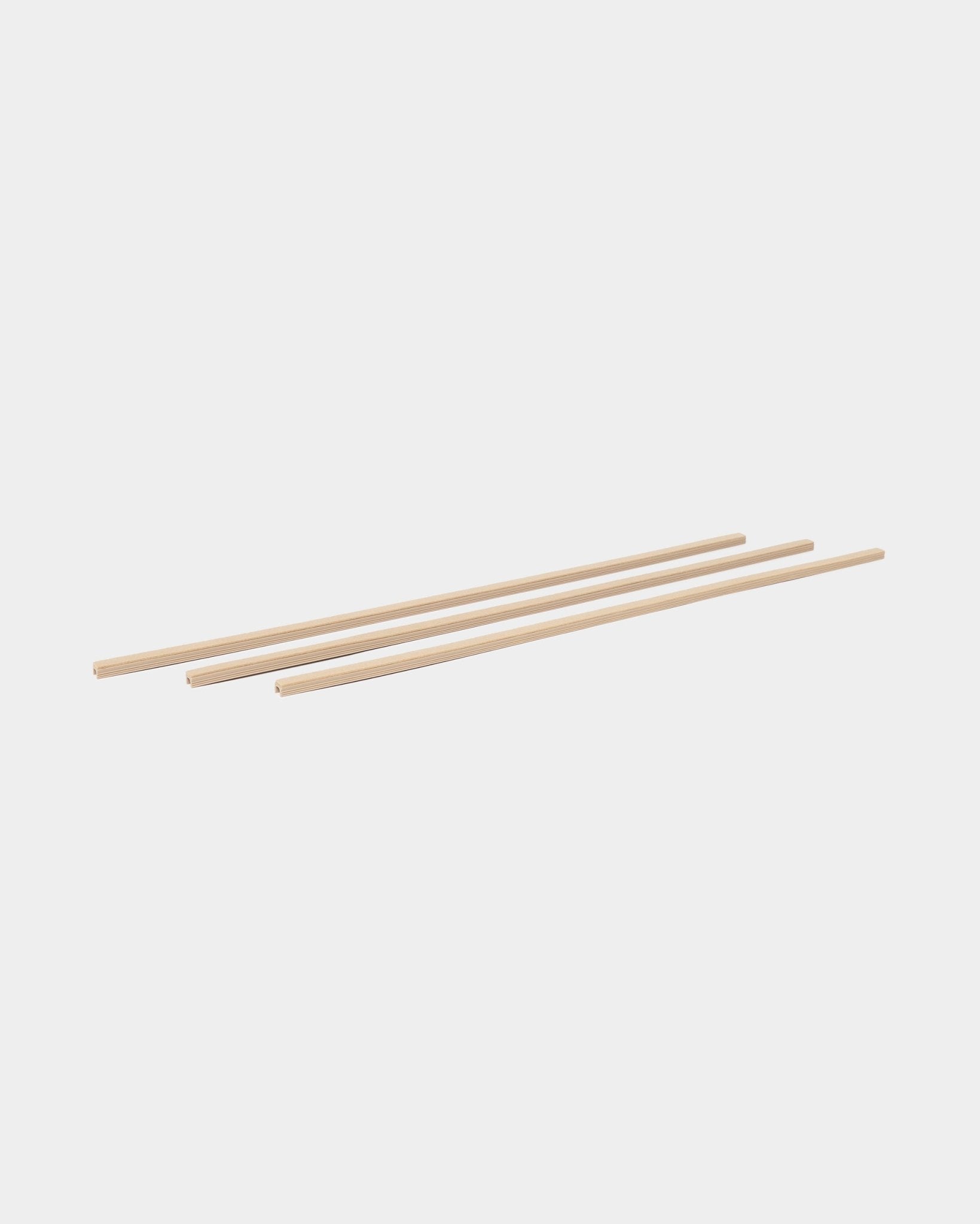 Tre beige Dupps Pop-on Cable Covers (3 deler) fra WoodUpp, en del av tilbehørskolleksjonen CREATE, plassert parallelt på en hvit bakgrunn.